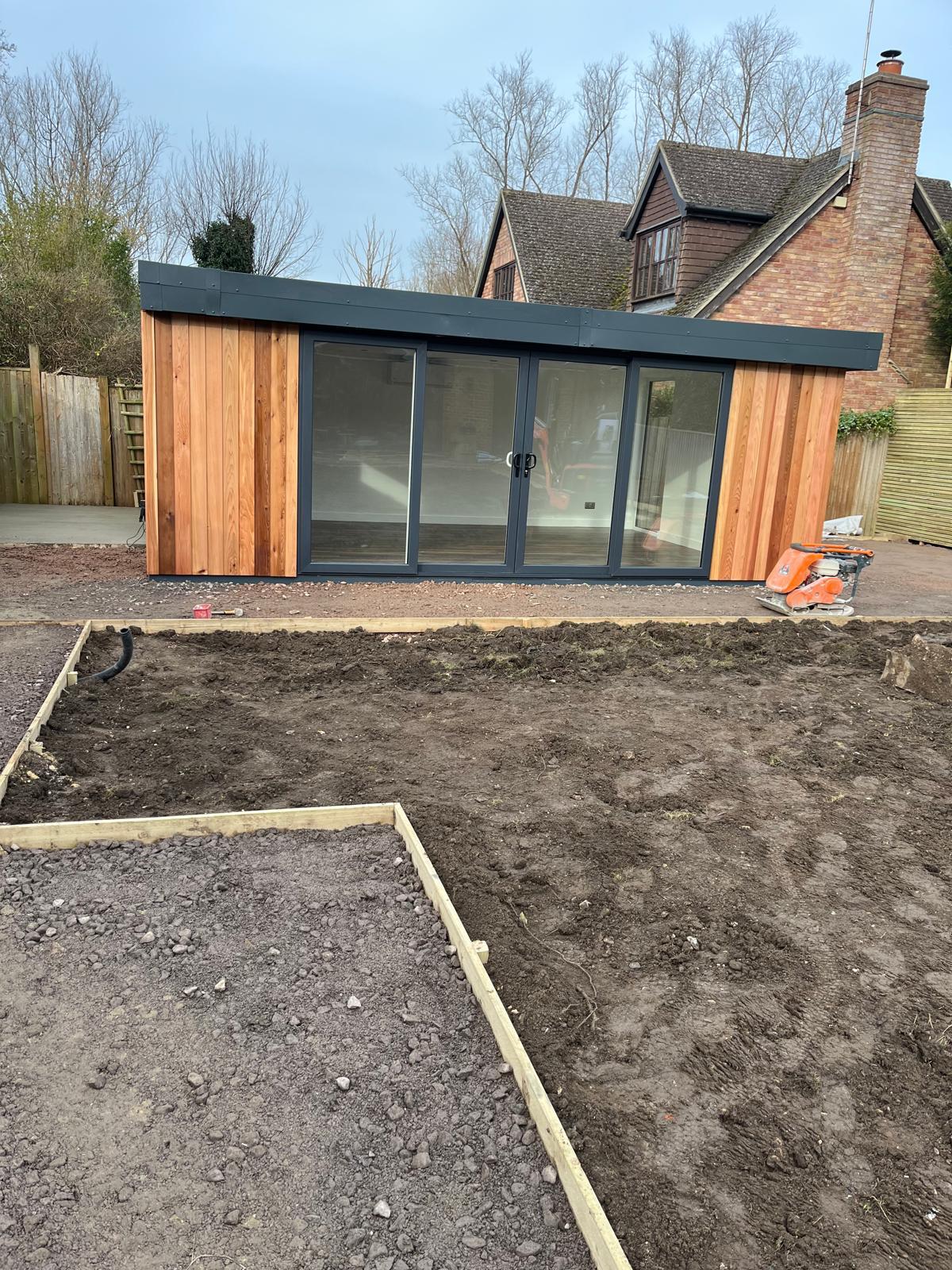 Garden room with timber cladding and glazed doors while the surrounding garden is being prepared