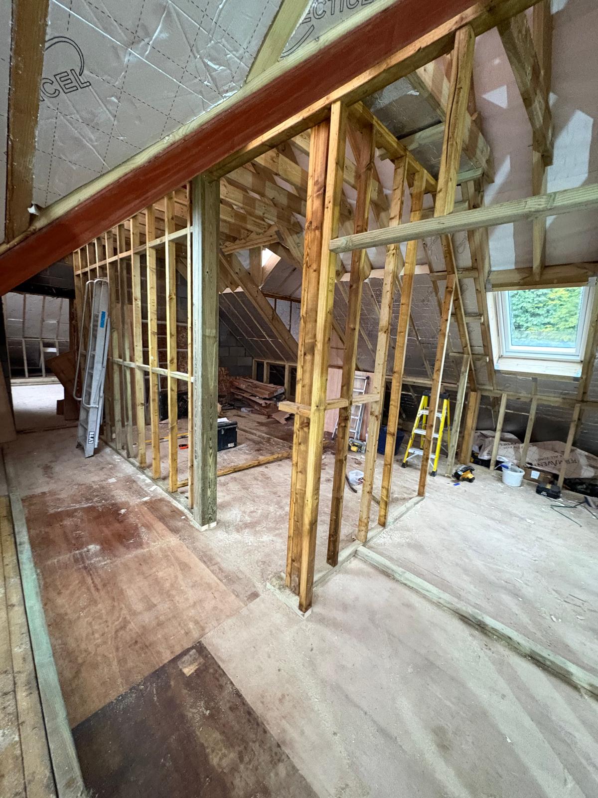 Timber stud walls and roof windows inside a loft under construction