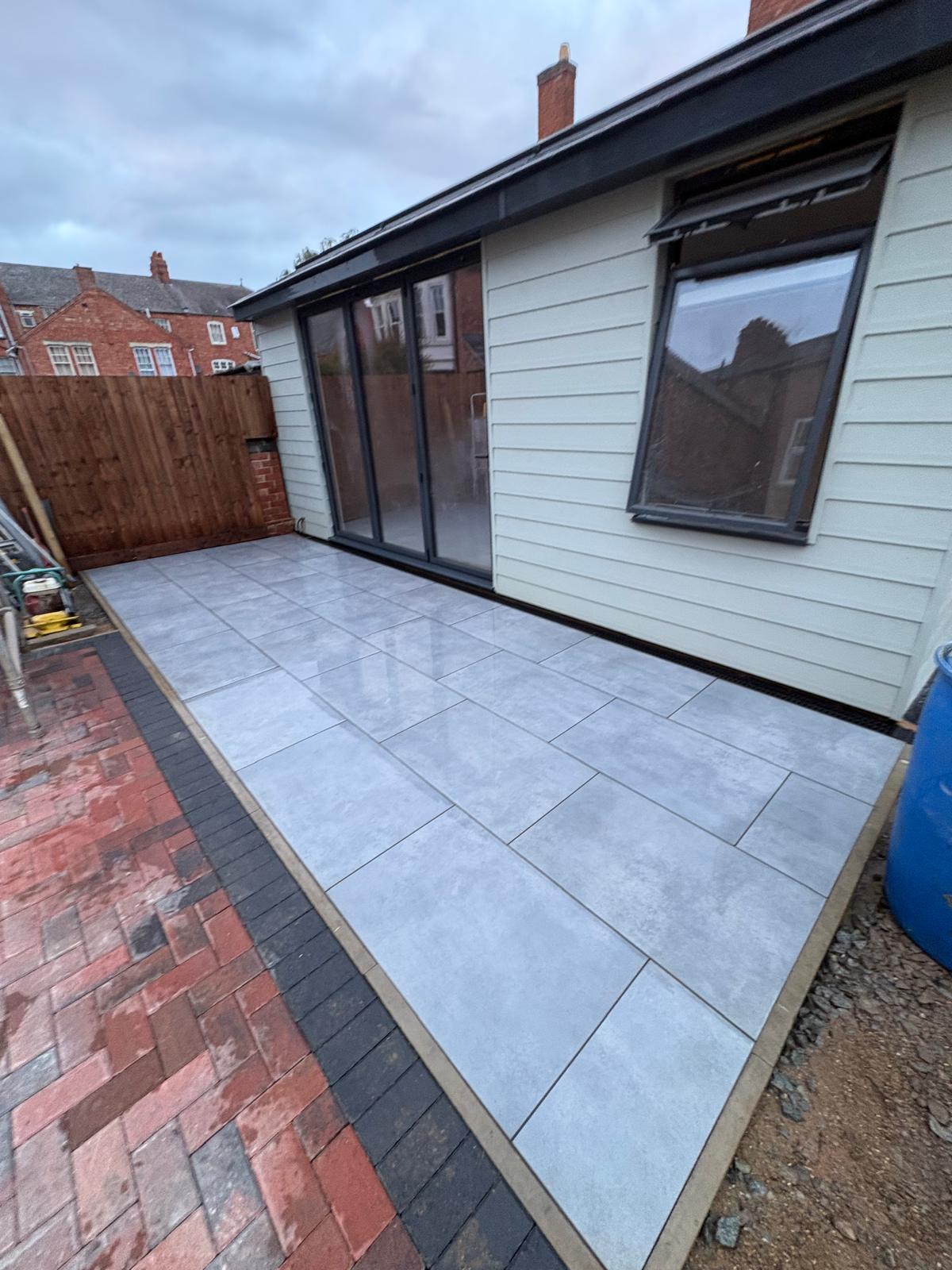 Completed pale grey patio beside a garden room