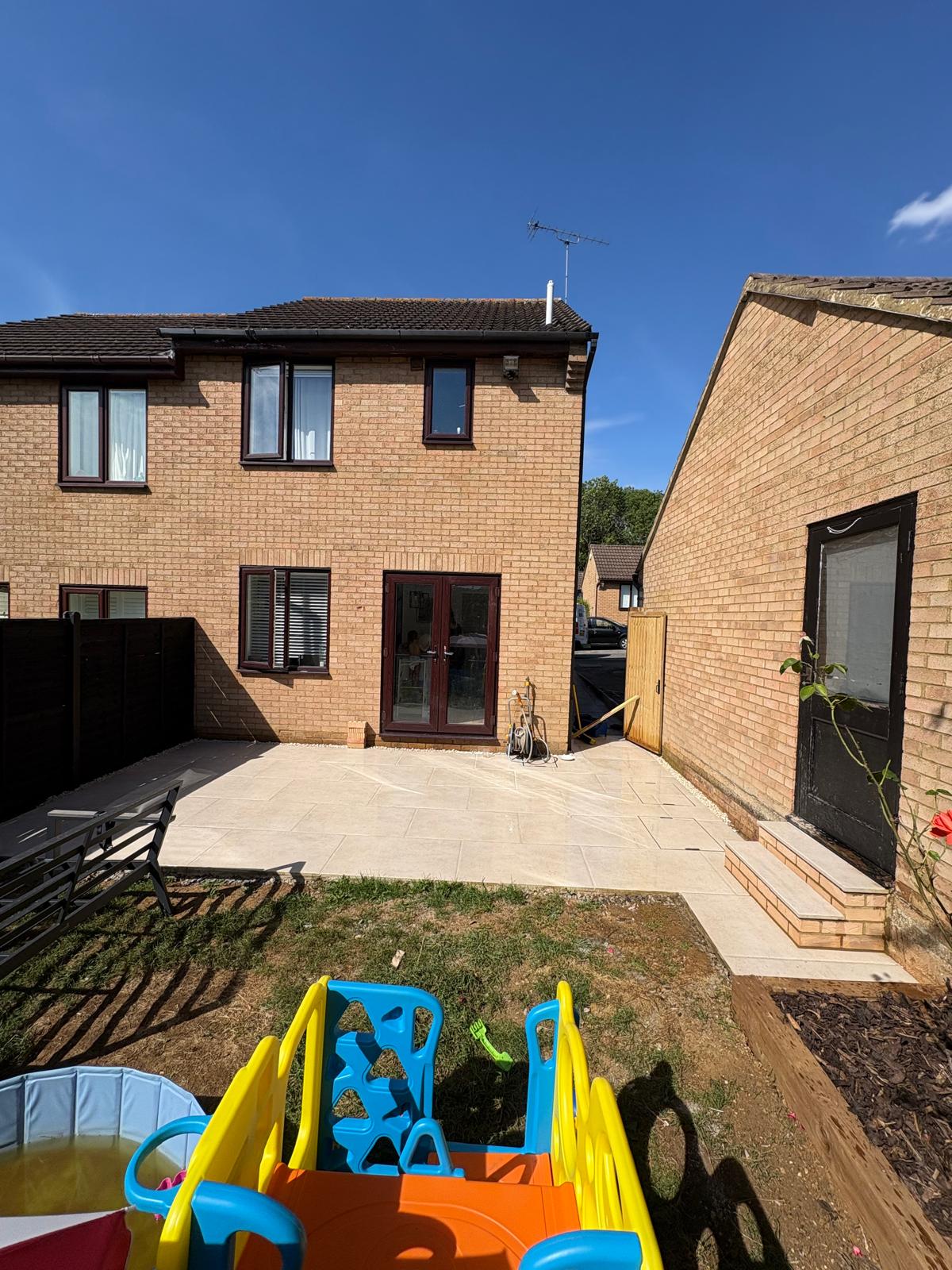 Wide view of light stone courtyard paving between a house and outbuilding